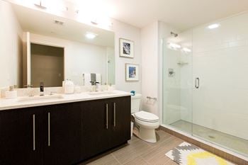 Spa baths with frameless glass shower, beautiful ebony vanity with dual sinks, large mirrors and hard surface flooring